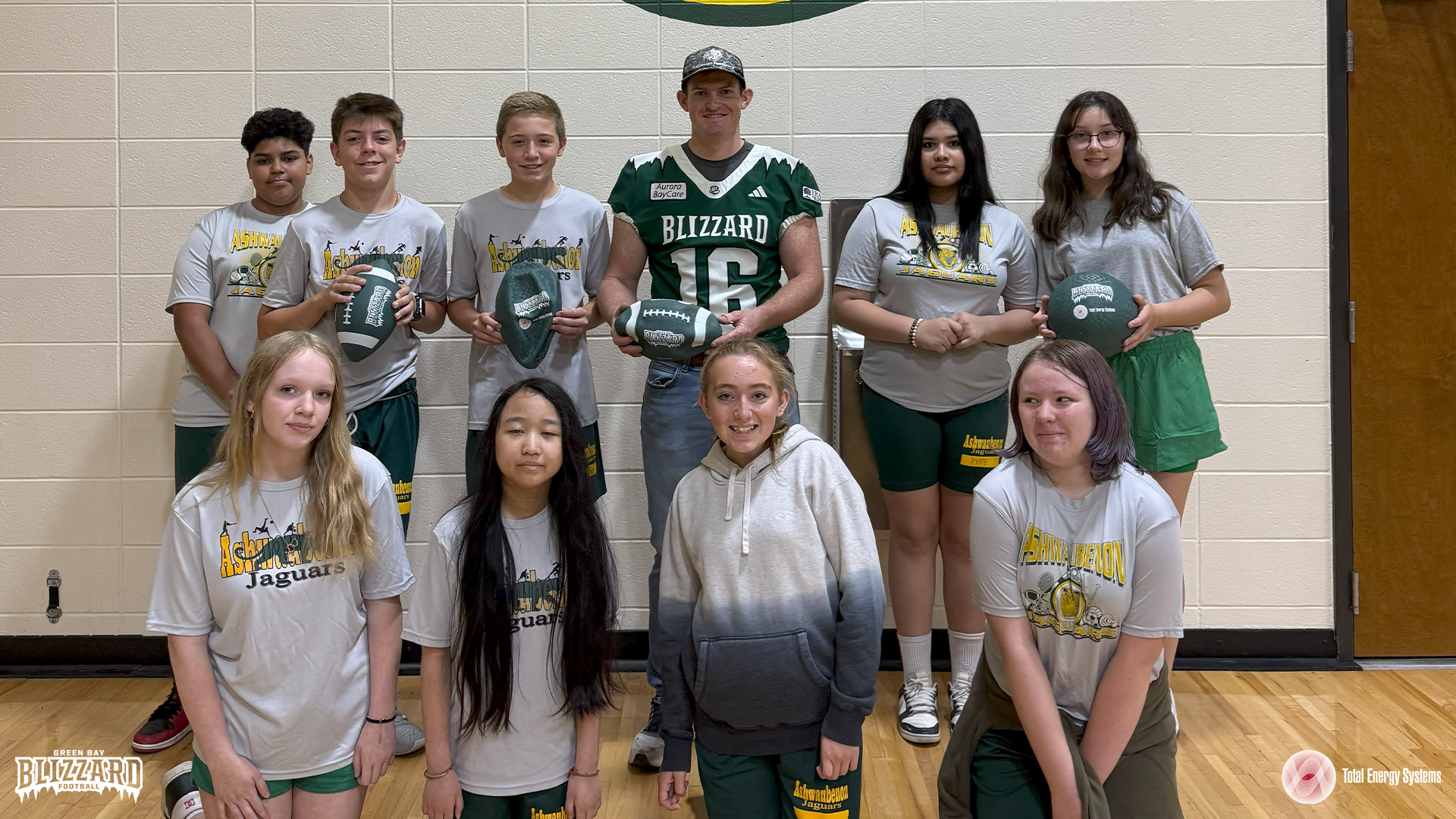 Blizzard kicker Andrew Mevis poses with students holding playground footballs and kickballs.